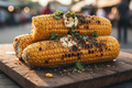 Grilled corn on the cob with butter, chilli and herbs on a rustic wooden board